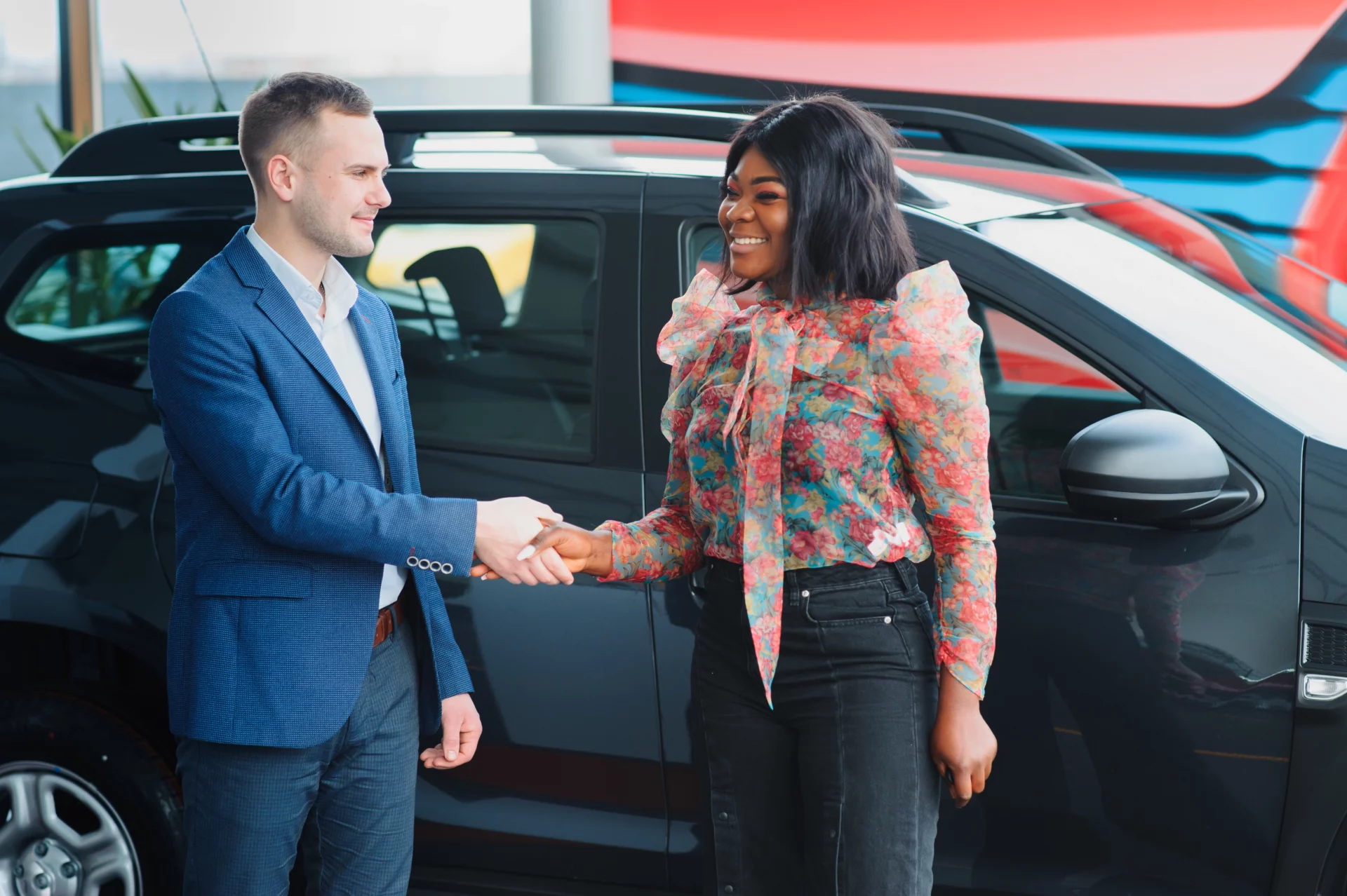 vendeur montrant une nouvelle voiture à un couple africain dans une salle d'exposition