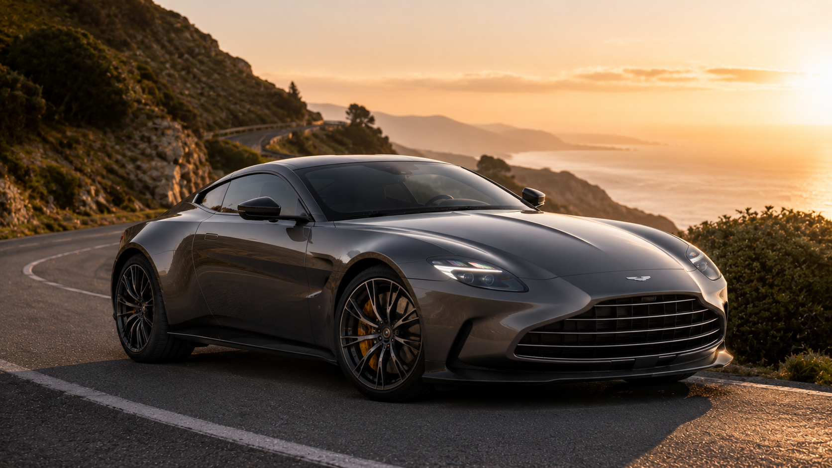 Aston Martin Vantage Aston Martin Vantage gris métallisé sur une route côtière sinueuse au coucher du soleil, photographie automobile haut de gamme mettant en valeur son design sportif, ses lignes aérodynamiques et ses jantes performance dans un décor naturel spectaculaire.