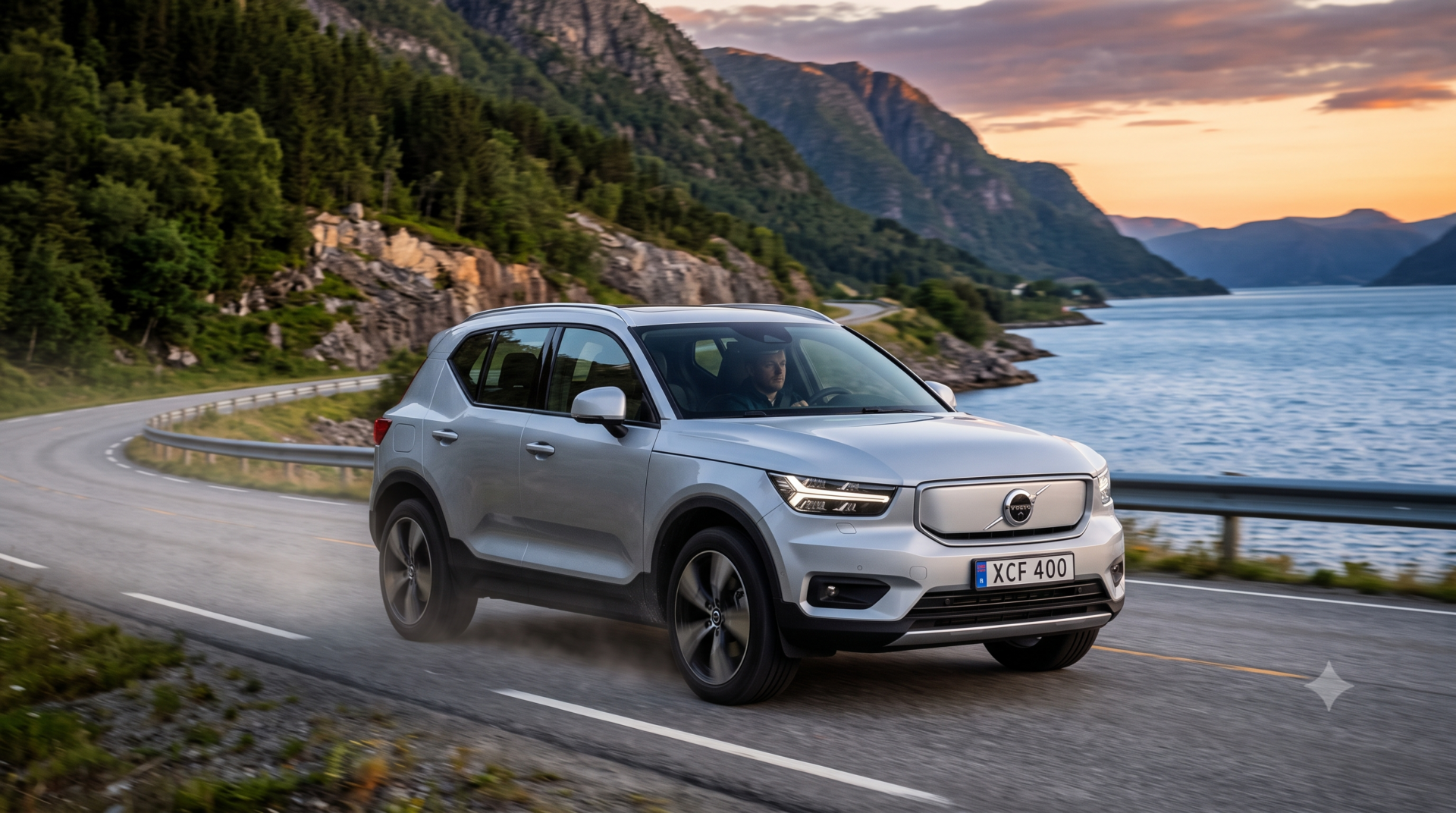 volvo XC40 SUV compact Volvo XC40 argenté circulant sur une route de montagne sinueuse bordant un fjord scandinave lors du coucher du soleil